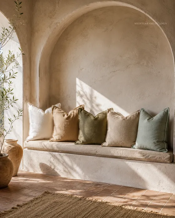 Five cream gray and sage cushions across a bright white sofa